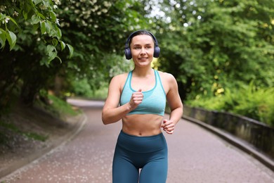 Photo of Sporty woman with headphones running in park