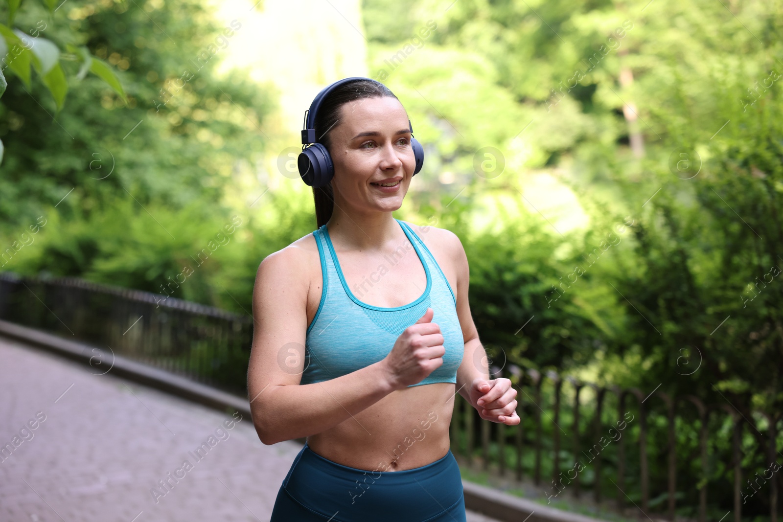 Sporty woman with headphones running in park Photo of Sporty woman with headphones running in park