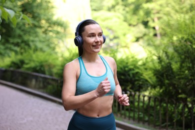 Photo of Sporty woman with headphones running in park