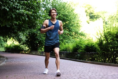 Photo of Sporty man with headphones running in park