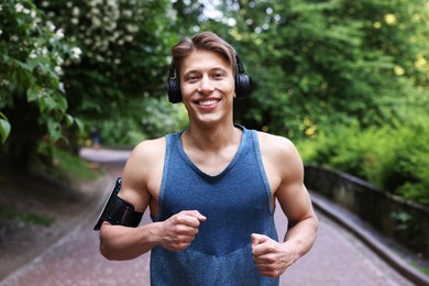 Photo of Sporty man with headphones running in park