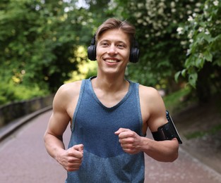 Photo of Sporty man with headphones running in park