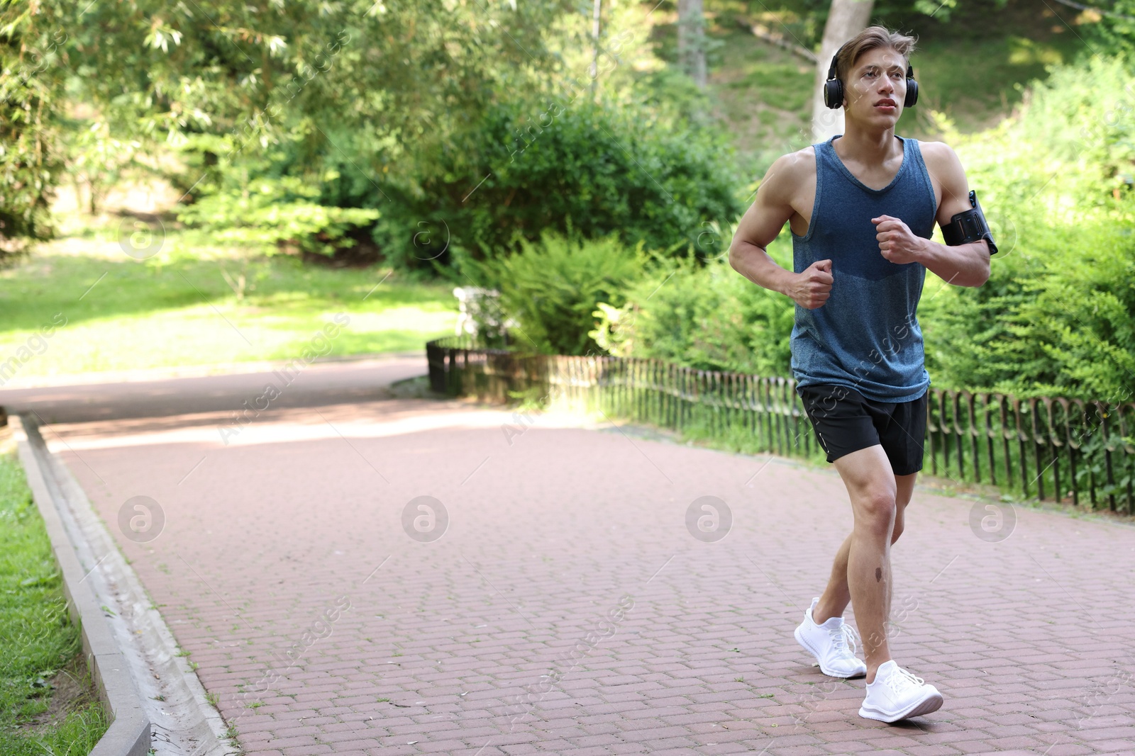 Sporty man with headphones running in park, space for text Photo of Sporty man with headphones running in park, space for text