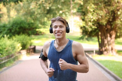 Photo of Sporty man with headphones running in park