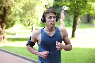 Photo of Sporty man with headphones running in park