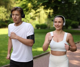 Photo of Sporty couple with headphones running in park
