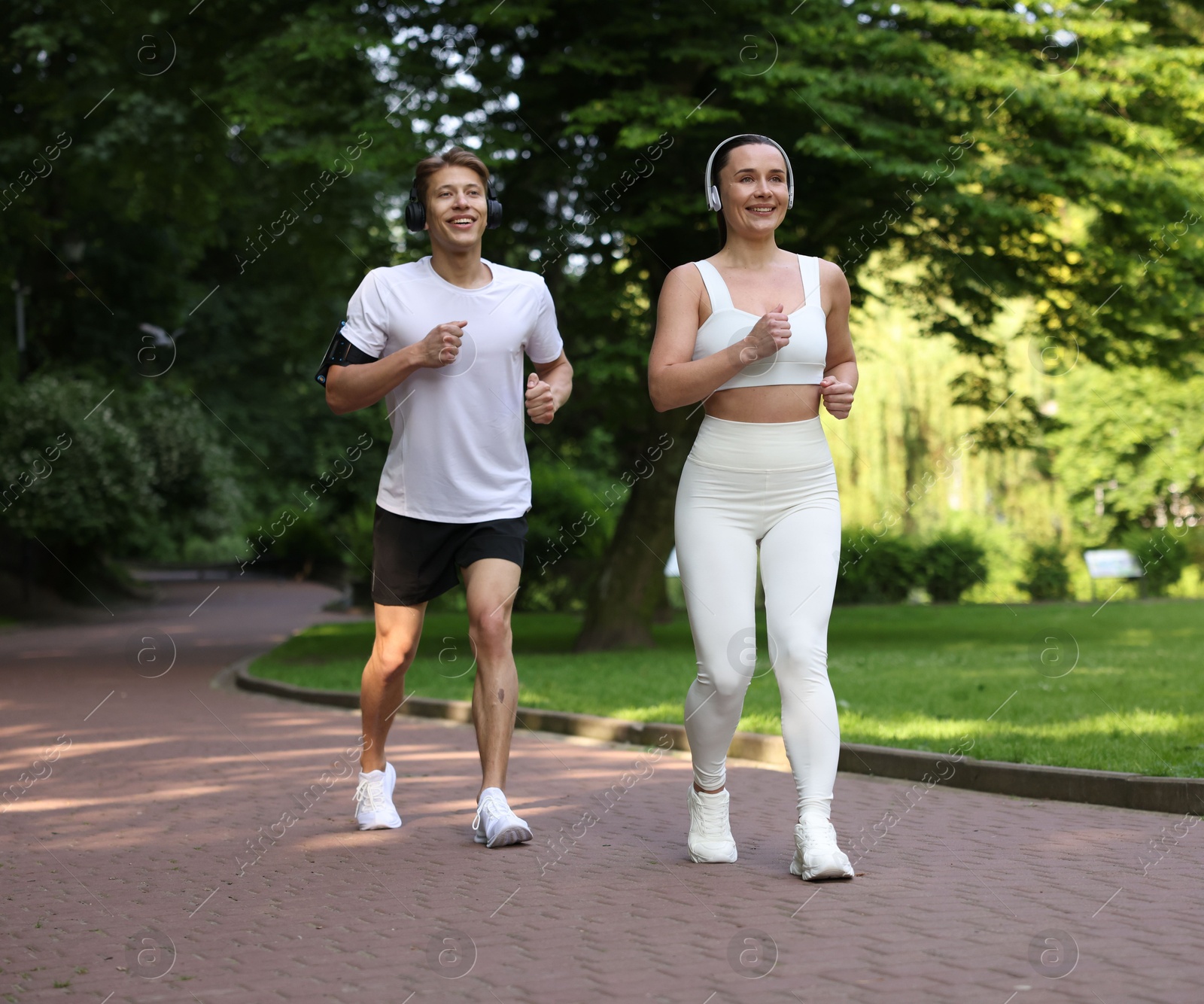 Sporty couple with headphones running in park Photo of Sporty couple with headphones running in park