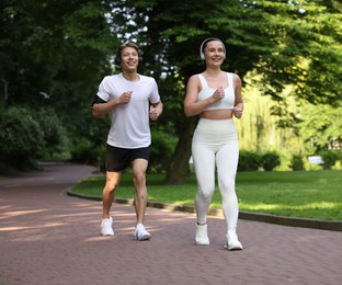 Photo of Sporty couple with headphones running in park