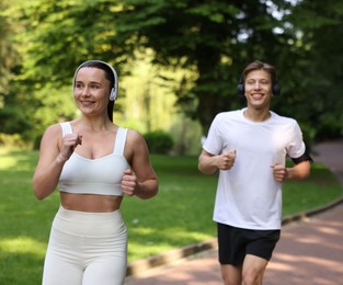 Photo of Sporty couple with headphones running in park