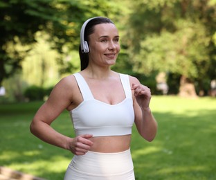 Photo of Sporty woman with headphones running in park