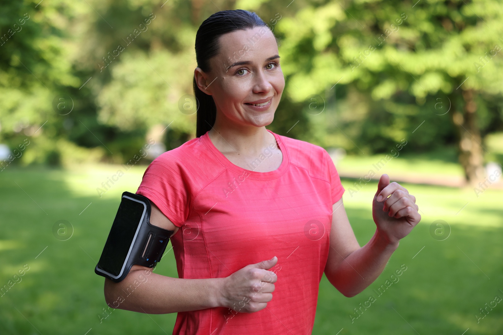 Sporty woman with armband running in park Photo of Sporty woman with armband running in park
