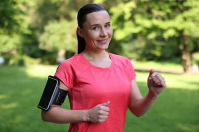 Photo of Sporty woman with armband running in park