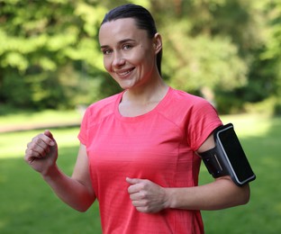 Photo of Sporty woman with armband running in park
