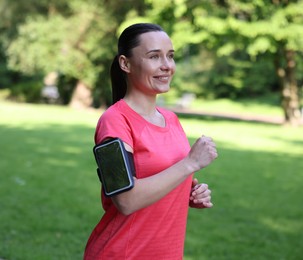 Photo of Sporty woman with armband running in park
