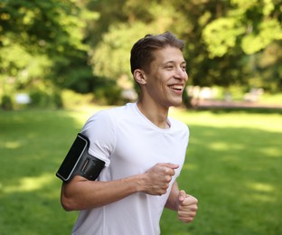 Photo of Sporty man with armband running in park