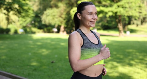 Photo of Sporty woman running in park, space for text