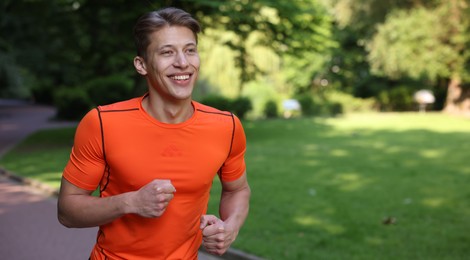 Photo of Sporty man running in park, space for text