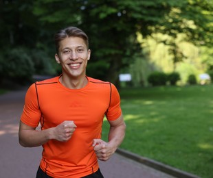 Photo of Sporty man running in park, space for text