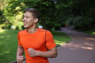 Photo of Sporty man running in park, space for text
