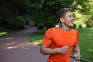 Photo of Sporty man running in park, space for text