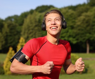 Photo of Sporty man with headphones running in park