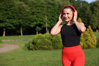 Photo of Happy woman in headphones outdoors, space for text. Healthy lifestyle
