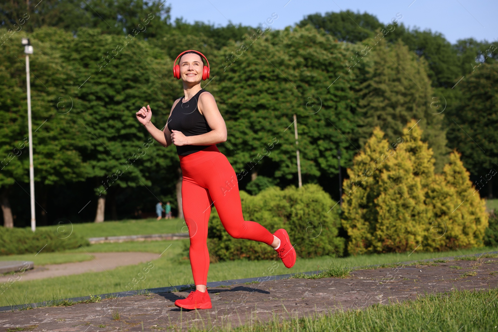 Sporty woman with headphones running in park Photo of Sporty woman with headphones running in park
