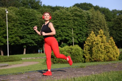 Photo of Sporty woman with headphones running in park