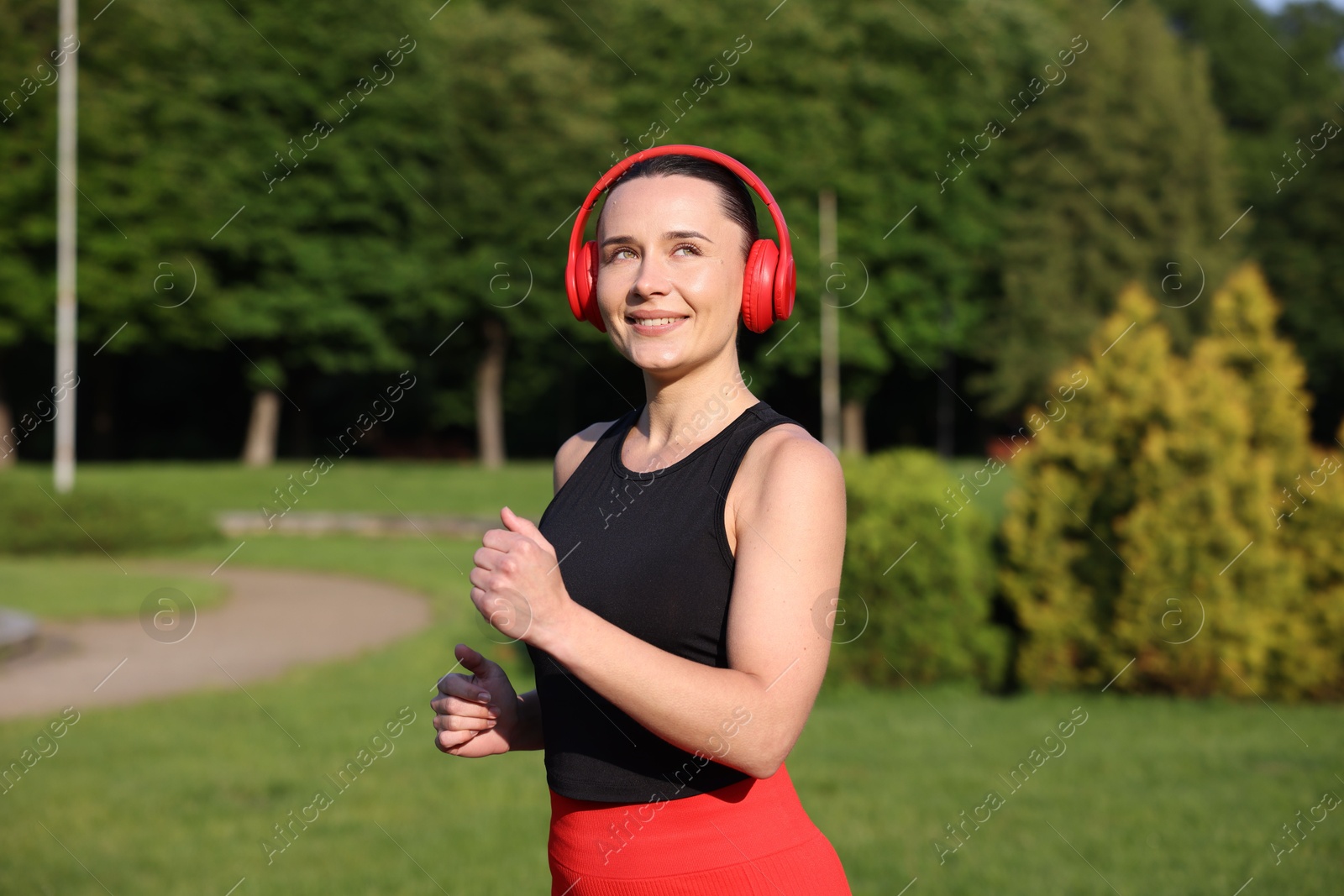 Sporty woman with headphones running in park Photo of Sporty woman with headphones running in park
