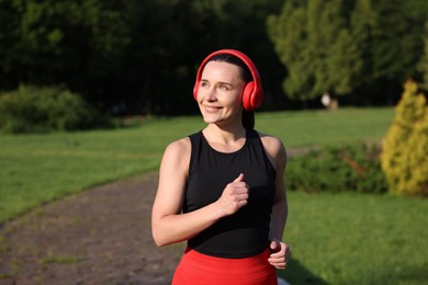 Photo of Sporty woman with headphones running in park