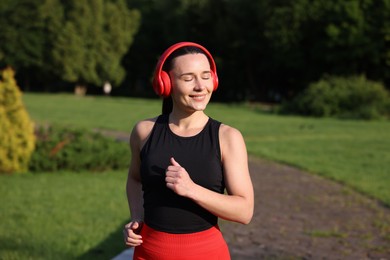 Photo of Sporty woman with headphones running in park