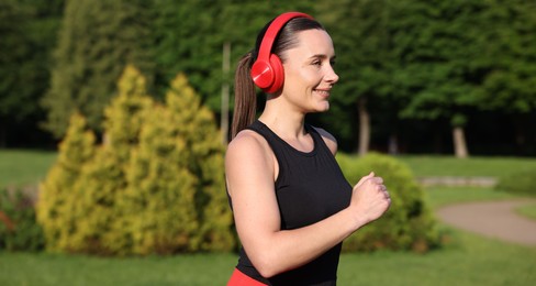 Photo of Sporty woman with headphones running in park