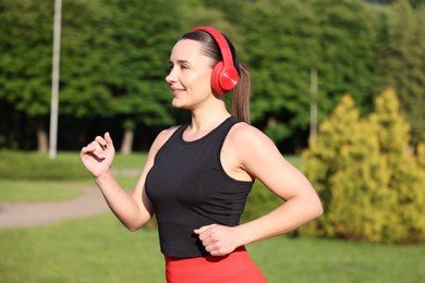 Photo of Sporty woman with headphones running in park