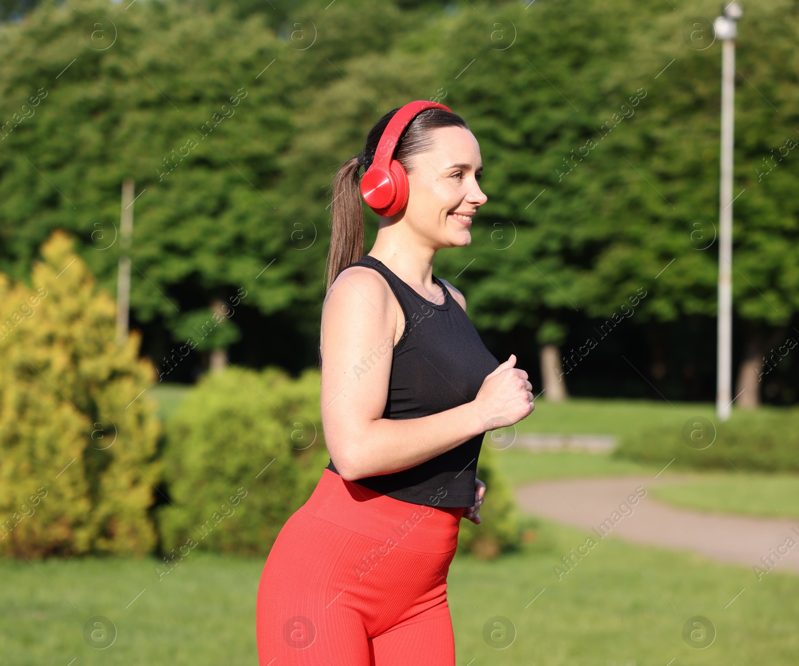 Sporty woman with headphones running in park Photo of Sporty woman with headphones running in park