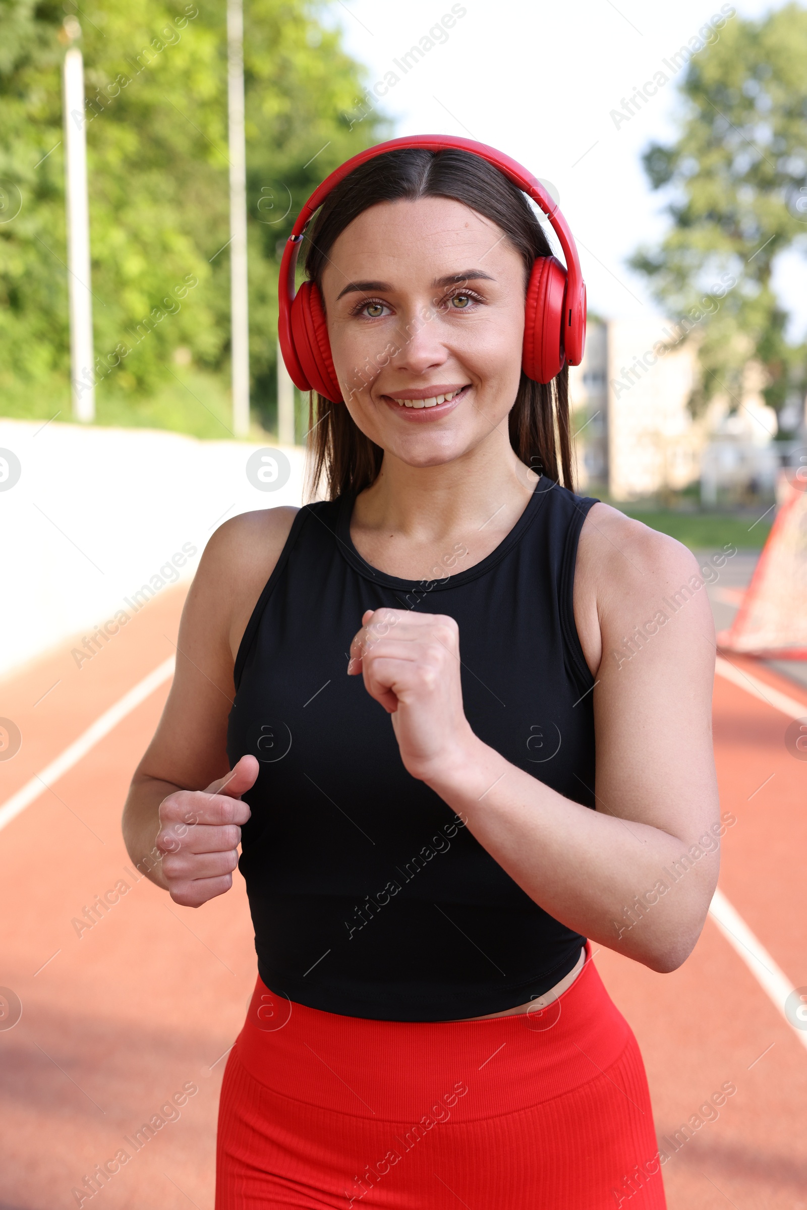 Sporty woman with headphones running at stadium Photo of Sporty woman with headphones running at stadium