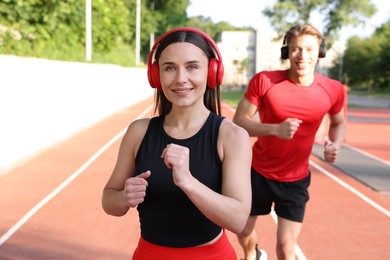 Photo of Sporty couple running at stadium, selective focus