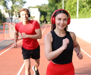 Photo of Sporty couple running at stadium, selective focus