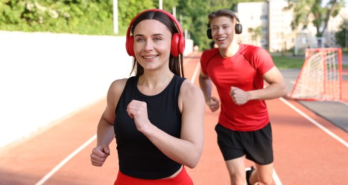 Photo of Sporty couple running at stadium, selective focus