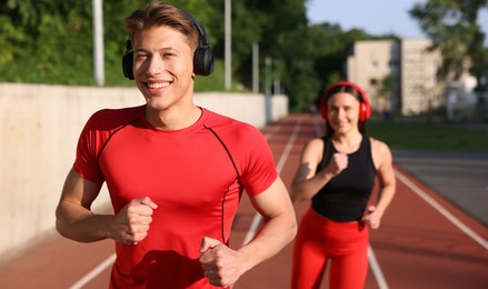 Photo of Sporty couple running at stadium, selective focus
