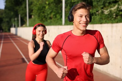 Photo of Sporty couple running at stadium, selective focus