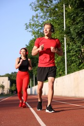 Photo of Sporty couple running at stadium, low angle view