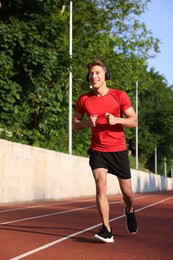 Photo of Sporty man with headphones running at stadium
