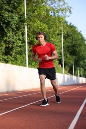 Photo of Sporty man with headphones running at stadium