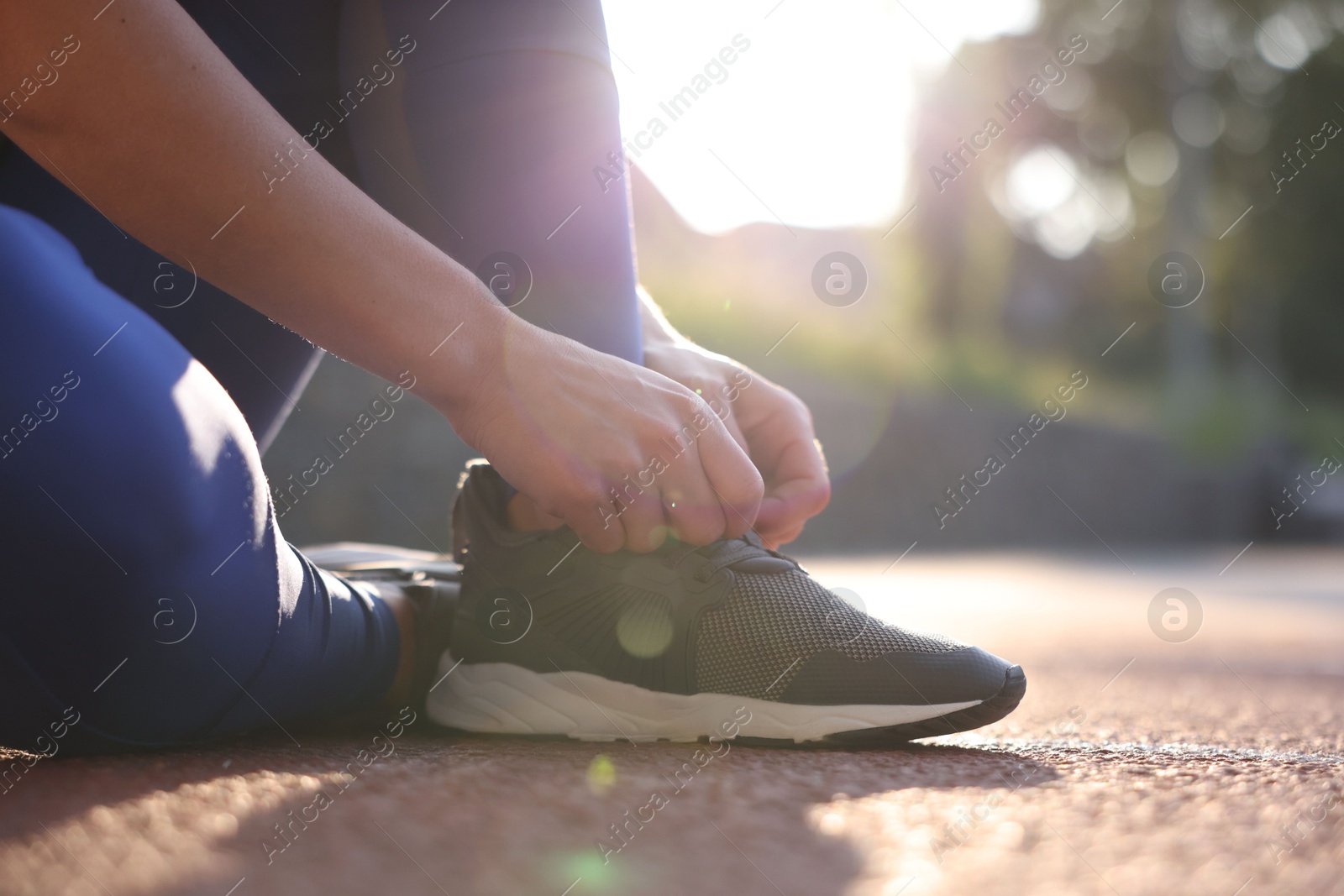 Photo of Woman tying shoelace of sneaker at stadium, closeup. Space for text