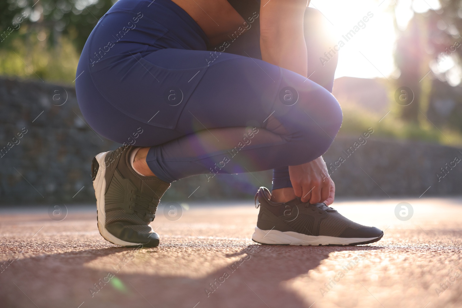 Woman tying shoelace of sneaker at stadium, closeup Photo of Woman tying shoelace of sneaker at stadium, closeup