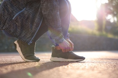 Photo of Woman tying shoelace of sneaker at stadium, closeup. Space for text