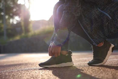 Photo of Woman tying shoelace of sneaker at stadium, closeup. Space for text