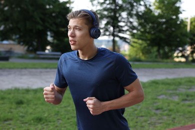 Photo of Sporty man with headphones running in park