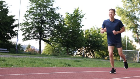 Photo of Sporty man running at stadium, space for text