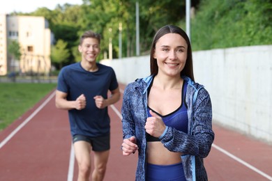 Photo of Sporty couple running at stadium, selective focus